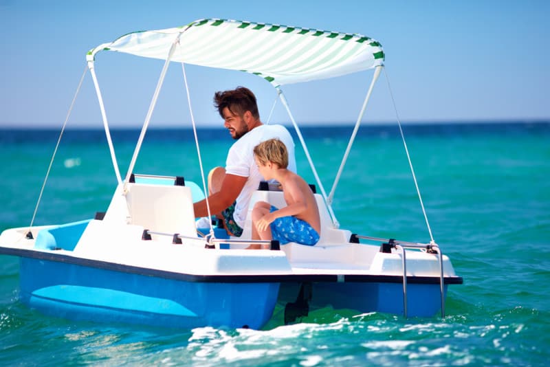 Happy family, father and son enjoy sea adventure on watercraft catamaran at summer vacation
