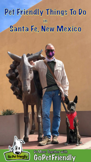 Man with brindle dog posing with the statue of a burro in Santa Fe, NM
