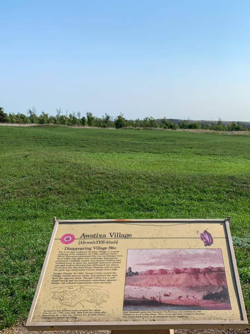 An informational sign about the Awatixa Village in front the open field where it used to exist