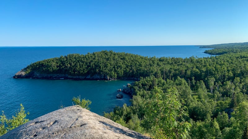 View from a large rock on a hill looking out toward a wooded peninsula in Lake Superior at Split Rock Lighthouse State Park in Minnesota