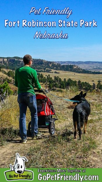 Man pushing a stroller and walking a black dog on a pet friendly trail in Fort Robinson State Park in Nebraska