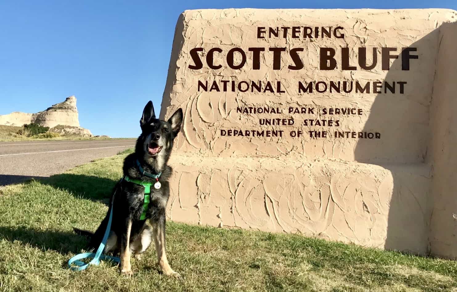 Black German Shepherd dog beside the Scotts Bluff National Monument sign