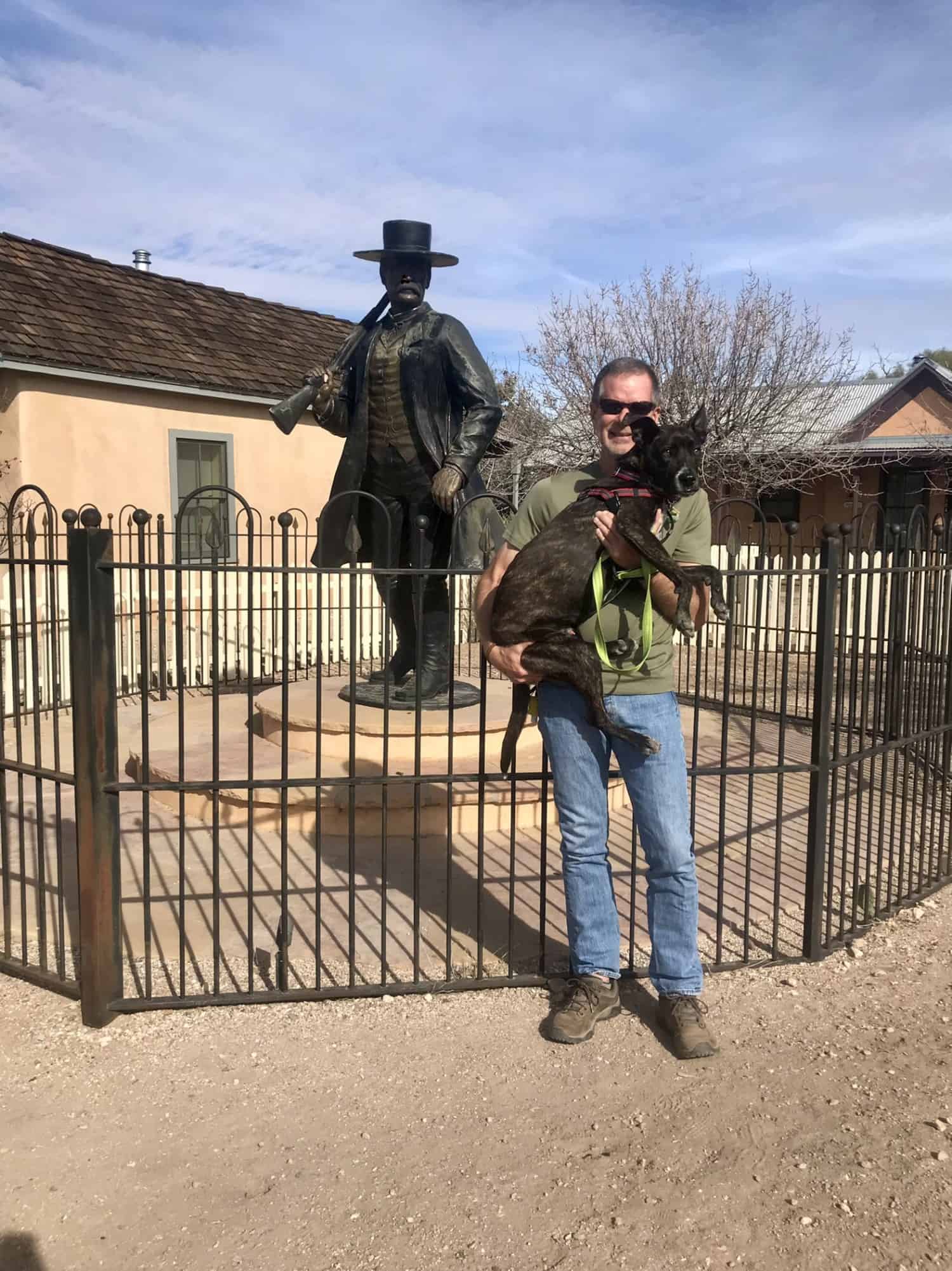 Man holding dog beside statue of Wyatt Earp in Tombstone, AZ