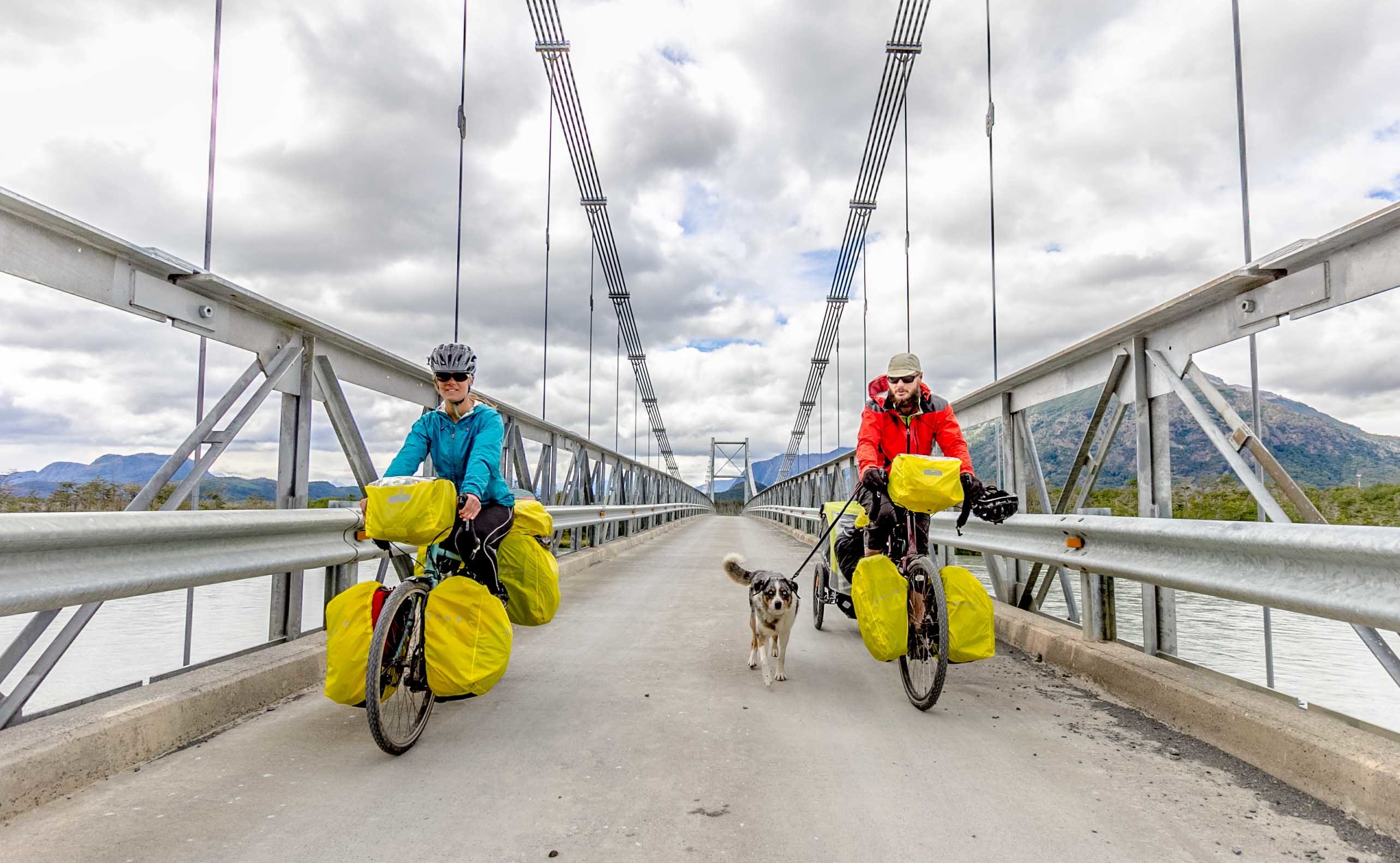 Two people on bicycles with a dog running between them