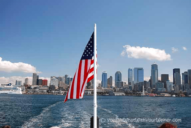 Flag on the back of a boat with the Seattle, WA skyline in the background