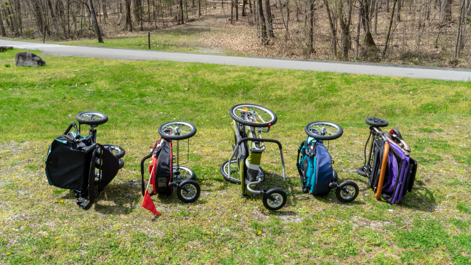 Five dog strollers in a folded position on their sides for comparison