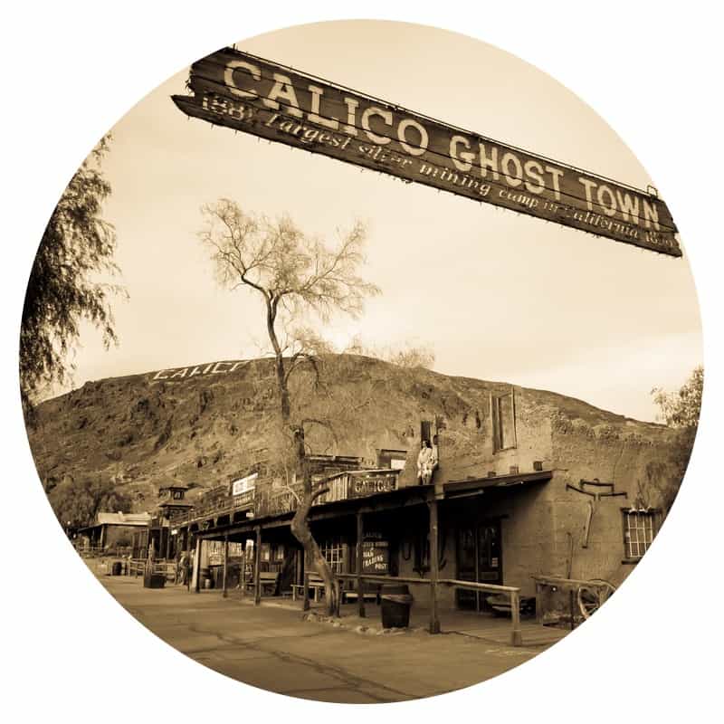 Black and white photo of a sign hanging over the street that says Calico Ghost Town. This is a pet friendly attraction along historic Route 66.