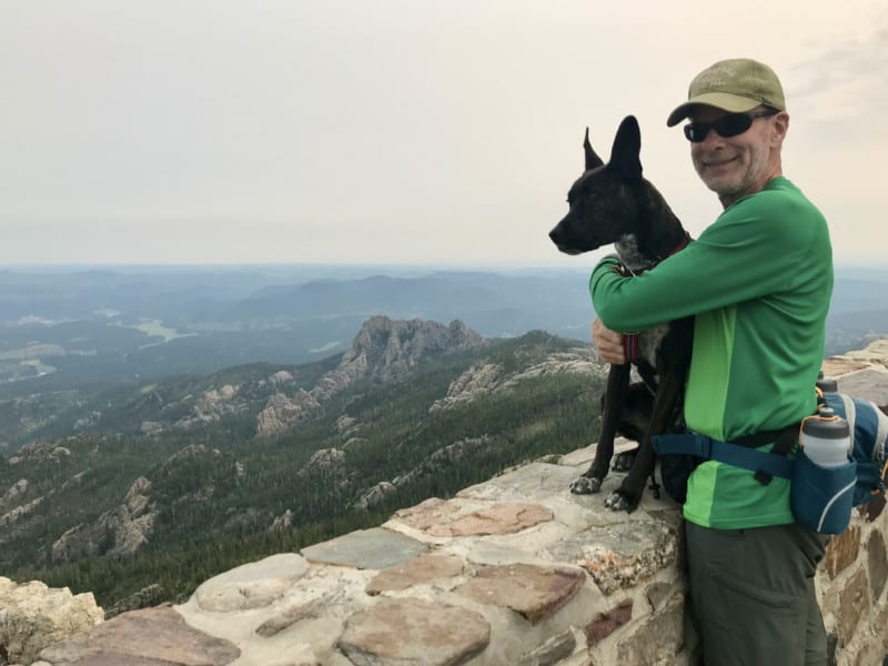 Man with a brindle dog at the fire tower on Black Elk Peak in the Black Hills, South Dakota