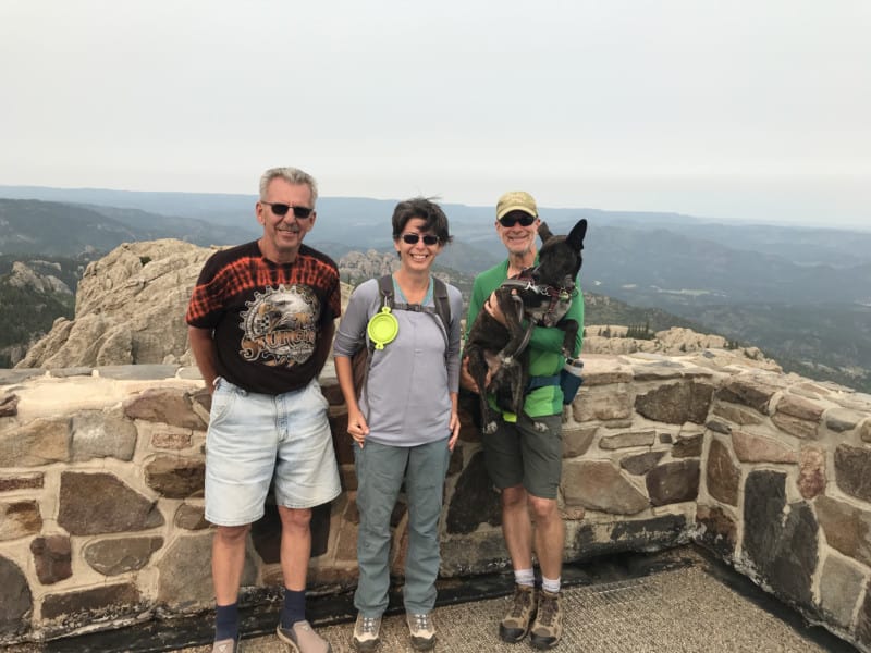 Two men, a woman, and a dog at the fire tower on Black Elk Peak in the Black Hills, South Dakota