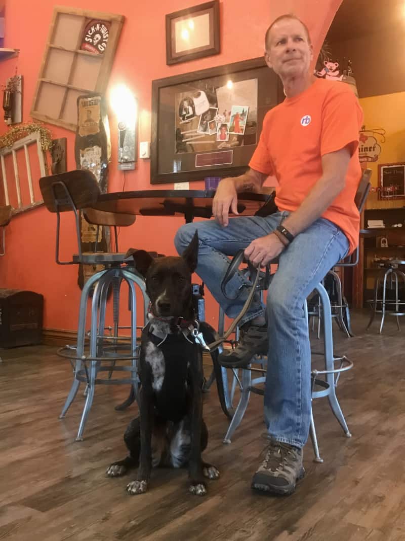 Brindle dog and man at pet friendly Naked Winery Tasting Room & Sick-N-Twisted Brew Pub in Hill City, SD