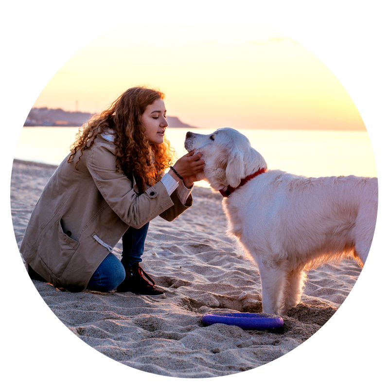 Woman in a jacket and a Golden Retriever dog on the beach in Virginia Beach, VA