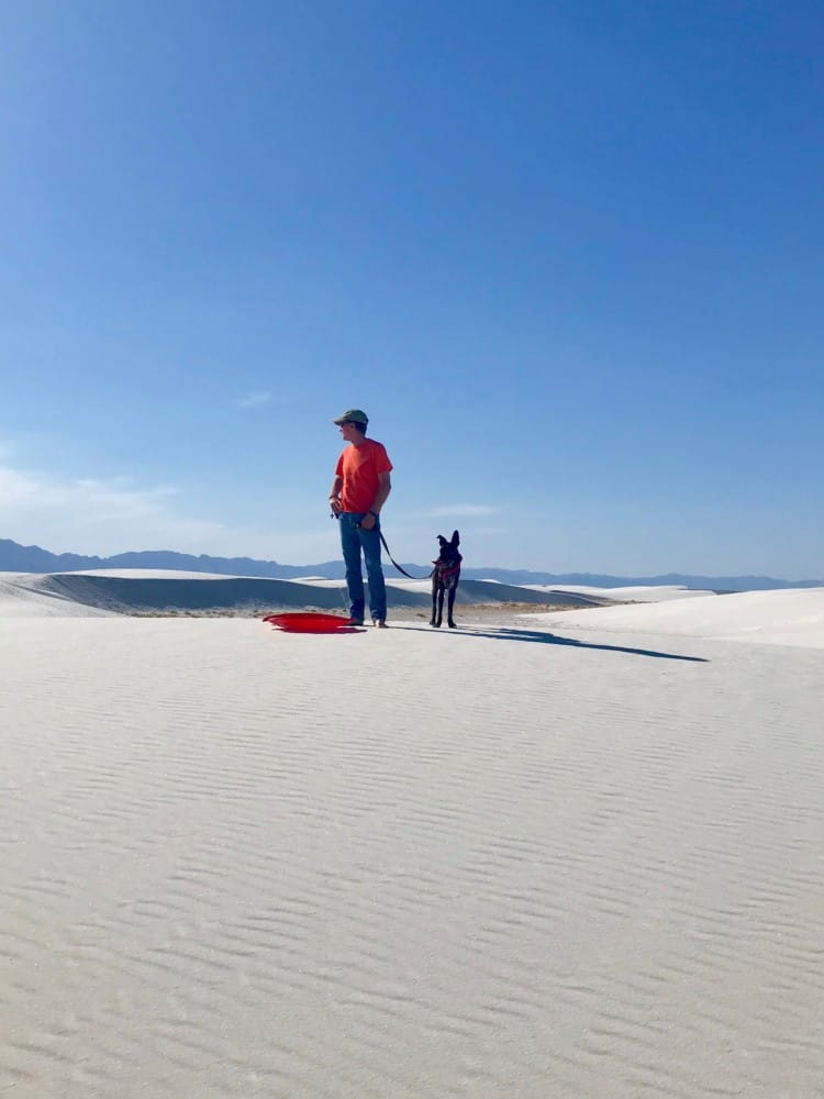 Man and dog with red sled in dog friendly White Sands National Park, NM