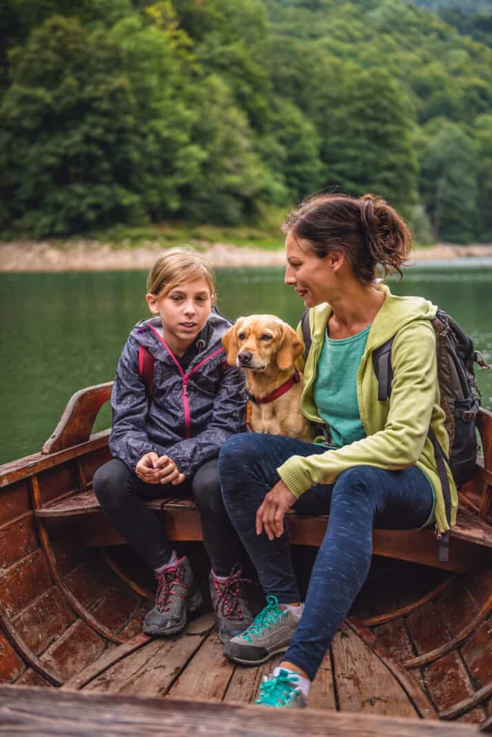 Mother and daughter with a dog sitting in a boat