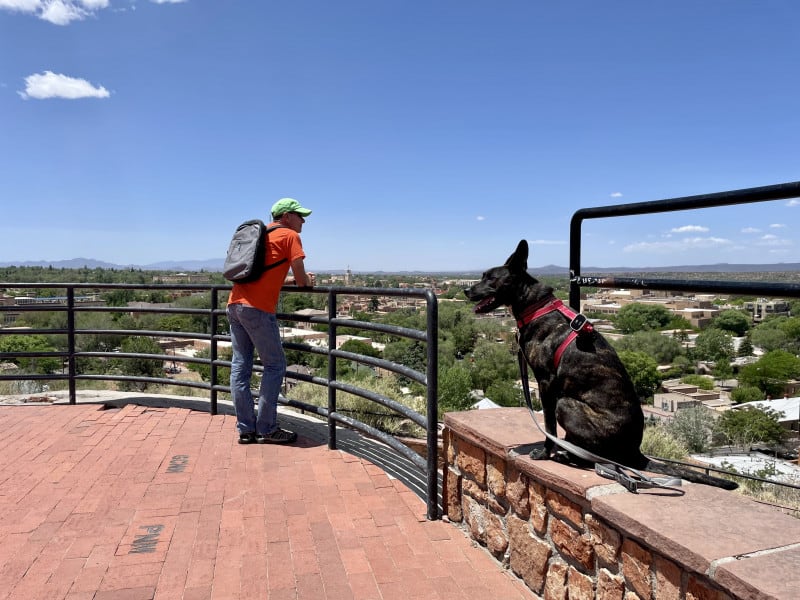 Man and smiling dog at the Cross of the Martyrs overlook in downtown Santa Fe, NM