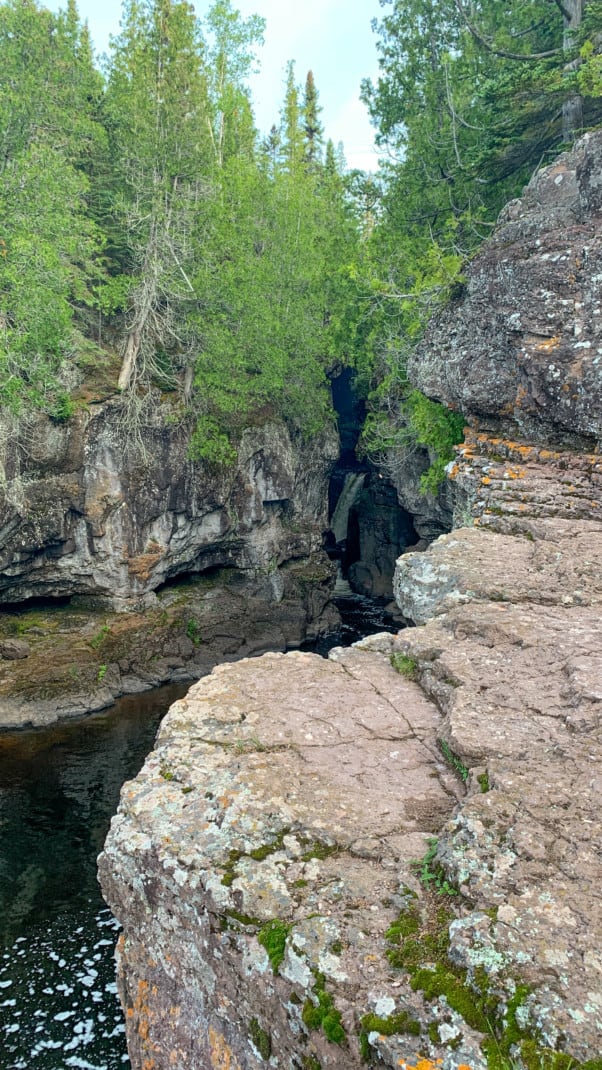 A waterfall can barely bee seen through the opening of a pine tree speckled gorge at Temperance River State Park on the North Shore in Minnesota.