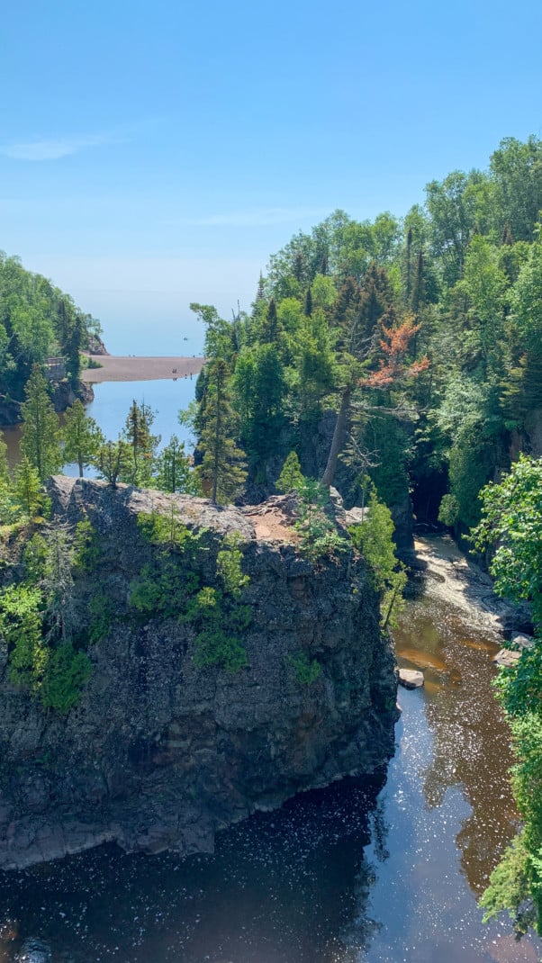 A river cuts through a pine tree studded gorge and empties into a lake at Tettegouche State Park on the North Shore in Minnesota