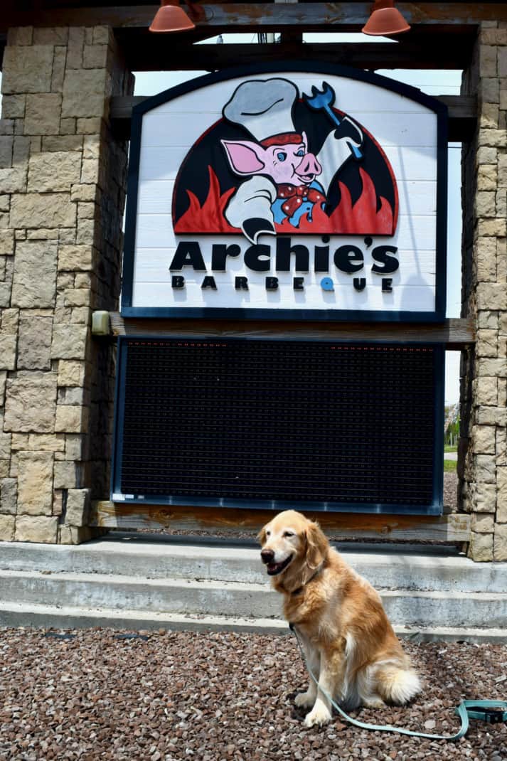 Golden Retriever sitting in front of an Archies BBQ sign