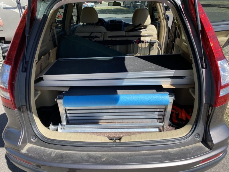 Collapsible steps, deck, and dog ramp folded up in the storage area of a Honda CRV