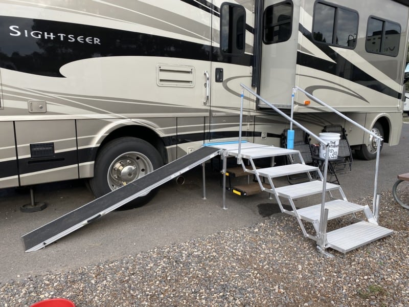 Folding deck and stairs with a dog ramp set up against a motorhome