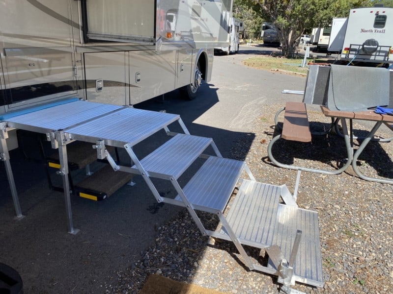 Side view of folding deck and stairs set up against a motorhome