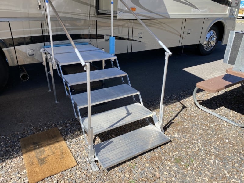 Folding deck and stairs set up against a motorhome