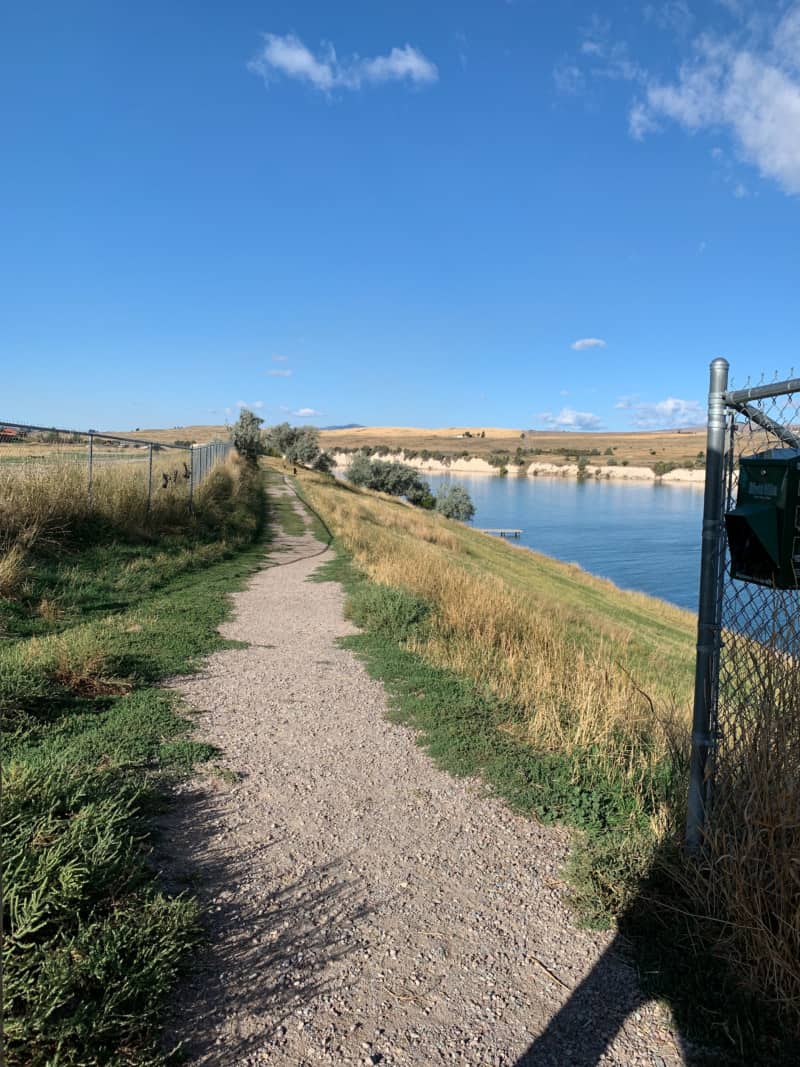 A grassy hill and lake at a dog park in Polson, Montana