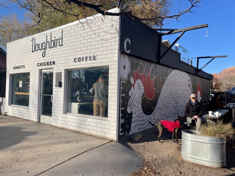 Woman and a dog in a red sweater at the outdoor seating area at Doughbirds donut shop in Moab, UT