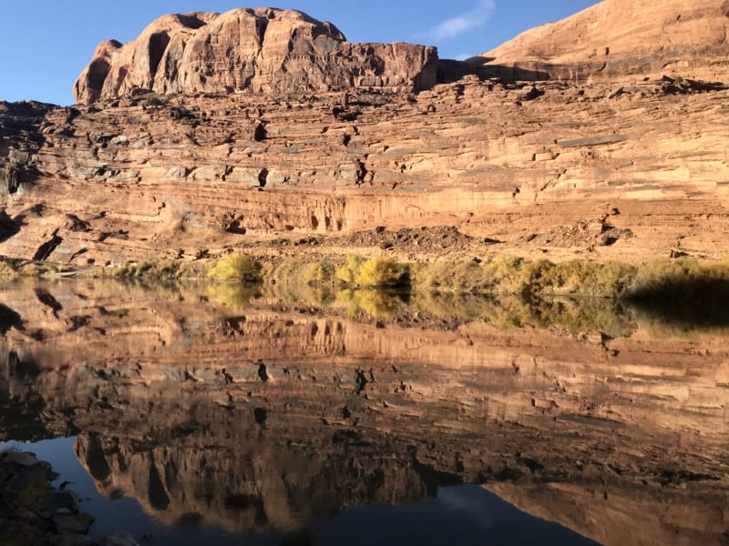 A red rock cliff and its reflection in the Colorado River taken from the Moab Canyon Pathway in Moab, UT