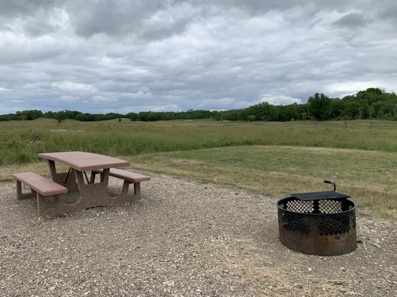 A gravel campsite with a picnic table and fire ring in the national grasslands of North Dakota