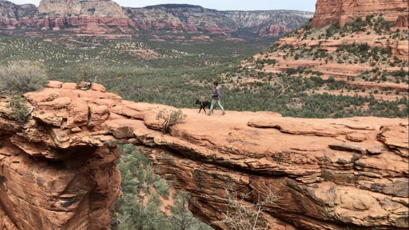 Woman and dog walking on Devils Bridge in Sedona, AZ