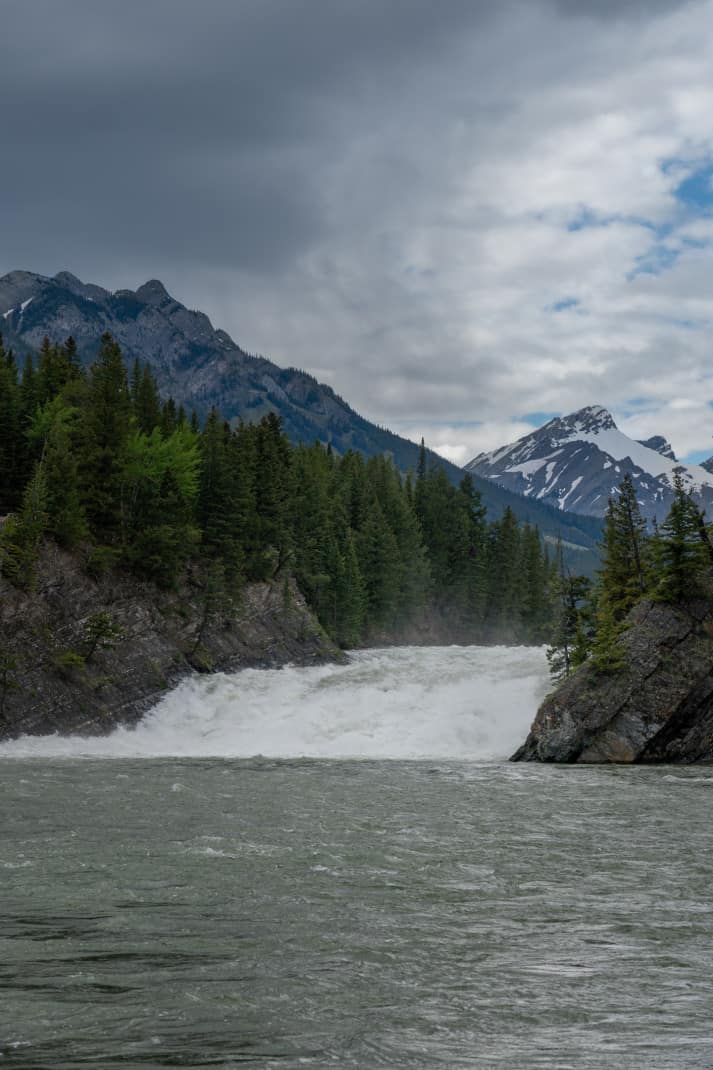Bow Falls. A rushing waterfall with mountains in the background.
