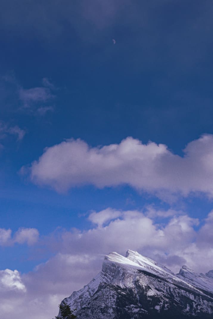 Close up of Mount Rundle with crescent moon above.