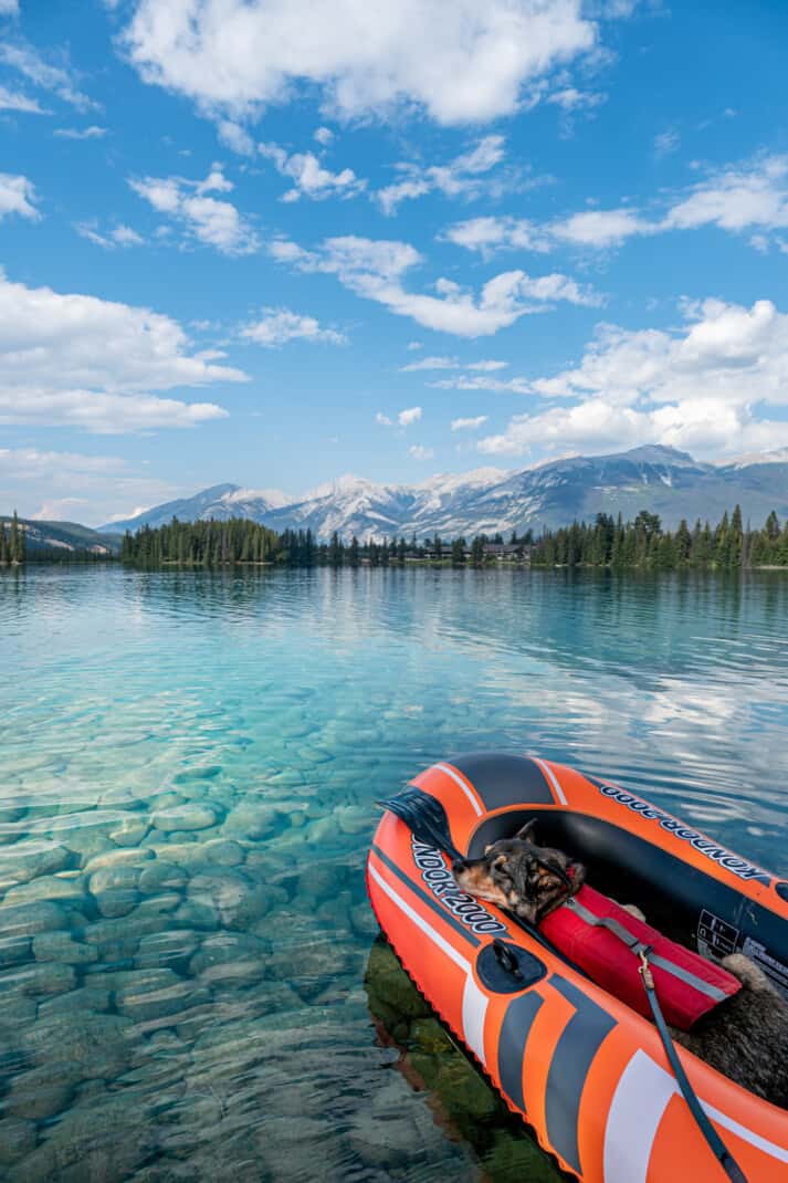 A cattle dog sleeping in an orange inflatable boat on the crystal clear waters of pet friendly Lac Beauvert in Jasper.