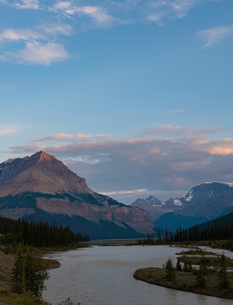 Image of sharp mountains glowing purple and pink along the Athabasca River in Jasper. Camping in Jasper National Park.