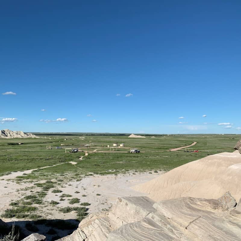 View from a hill looking down at a small camp ground in the grasslands at Toadstool Geologic Park